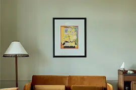 A refined living area with a mustard-colored velvet sofa, a marble coffee table, vintage-inspired armchairs, and a framed artwork on the pale wall.