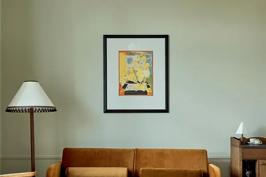 A refined living area with a mustard-colored velvet sofa, a marble coffee table, vintage-inspired armchairs, and a framed artwork on the pale wall.