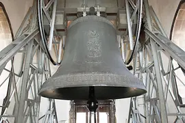 A close-up view of the massive Pummerin bell inside St. Stephen’s Cathedral’s bell tower, showing the intricate metal framework, supporting structure, and detailed reliefs on the bell.