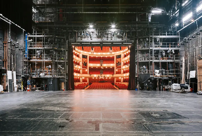 Blick von der Bühne des Burgtheaters auf den Zuschauersaal mit Reihen von Sitzen und dekorativer Innenarchitektur.