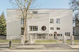 Street view of the modernist villa with circular window and recessed entrance.