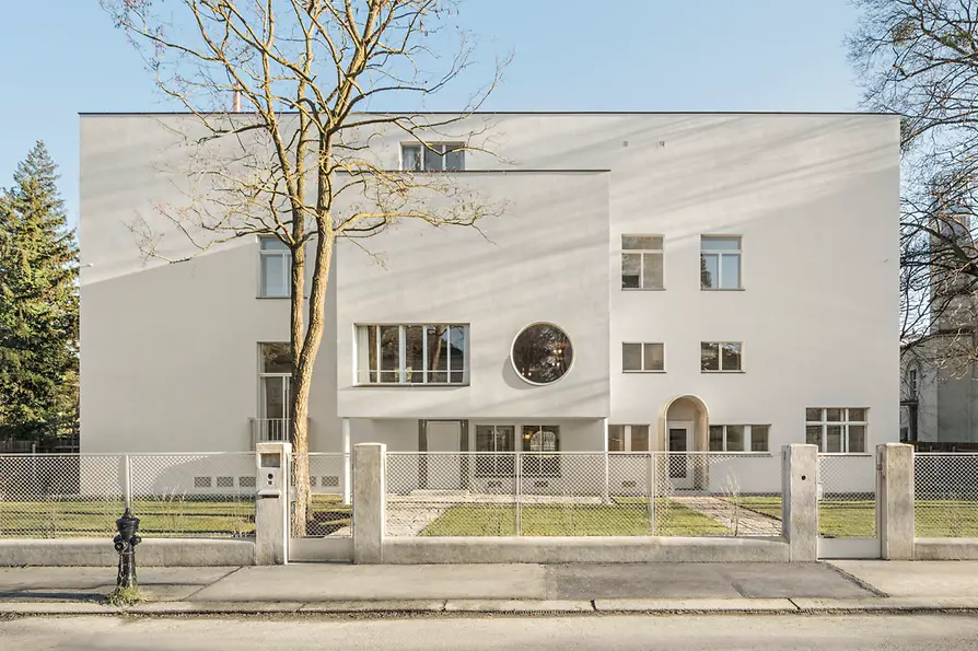 Street view of the modernist villa with circular window and recessed entrance.