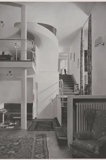 Historic view of the entrance hall with curved staircase and gallery.