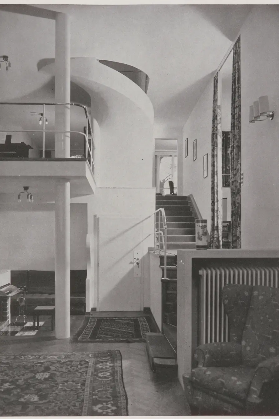 Historic view of the entrance hall with curved staircase and gallery.
