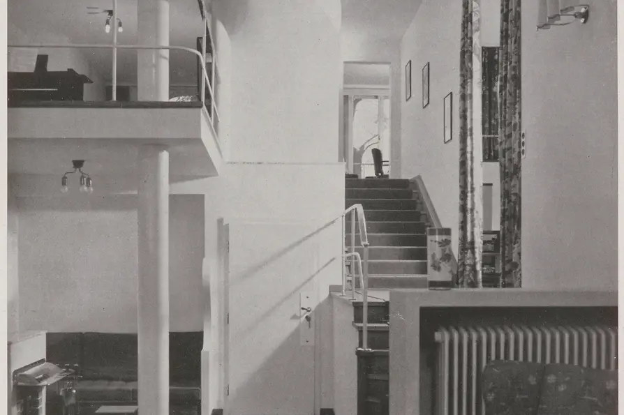 Historic view of the entrance hall with curved staircase and gallery.