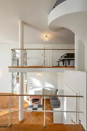 Gallery level overlooking the living space with parquet flooring and piano.