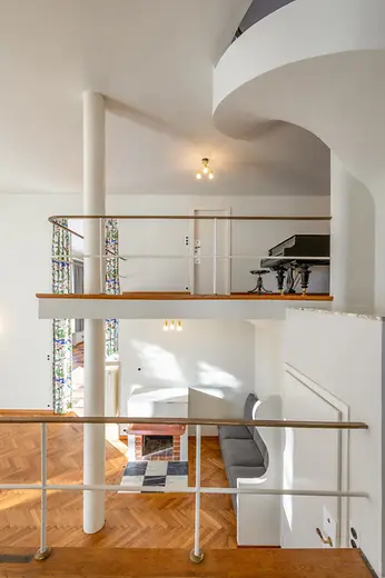 Gallery level overlooking the living space with parquet flooring and piano.
