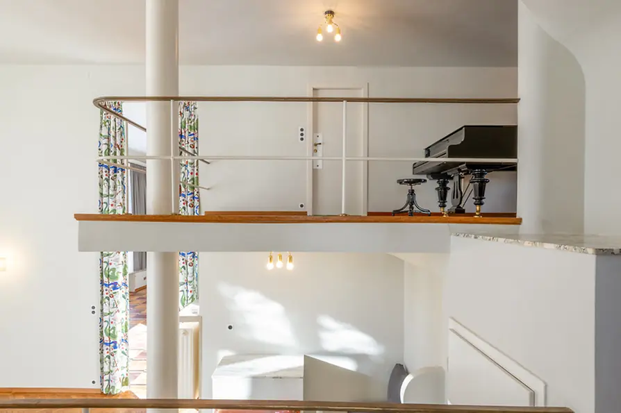 Gallery level overlooking the living space with parquet flooring and piano.