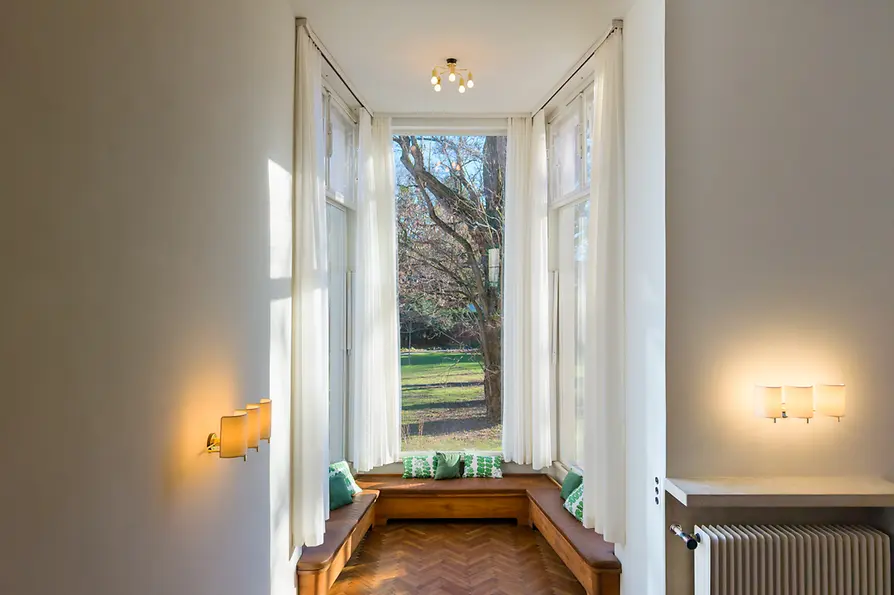 Bright interior with large windows, built-in benches, and view of the greenery.