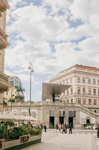 View of the Albertina with equestrian statue and modern entrance canopy in the city center.