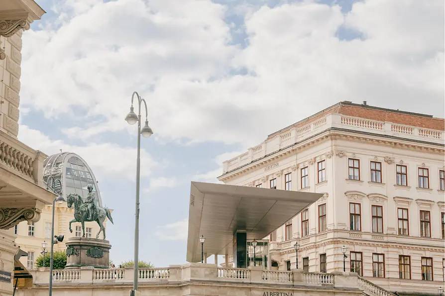 View of the Albertina with equestrian statue and modern entrance canopy in the city center.