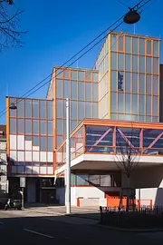 Modern Stadthallenbad building with orange glass façade and clean geometric lines.