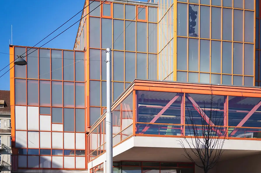 Modern Stadthallenbad building with orange glass façade and clean geometric lines.