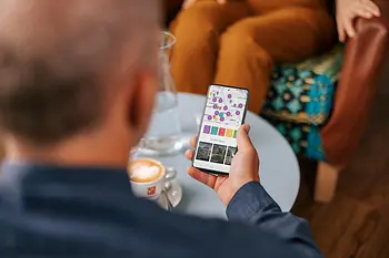 Person sitzt im Kaffee und nutzt die Smartphone-App ivie des WienTourismus mit Kartenansicht