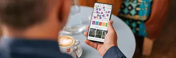 Person sitzt im Kaffee und nutzt die Smartphone-App ivie des WienTourismus mit Kartenansicht