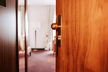 A half-open wooden door leading to a guest room at Hotel Stefanie. The key is in the lock.