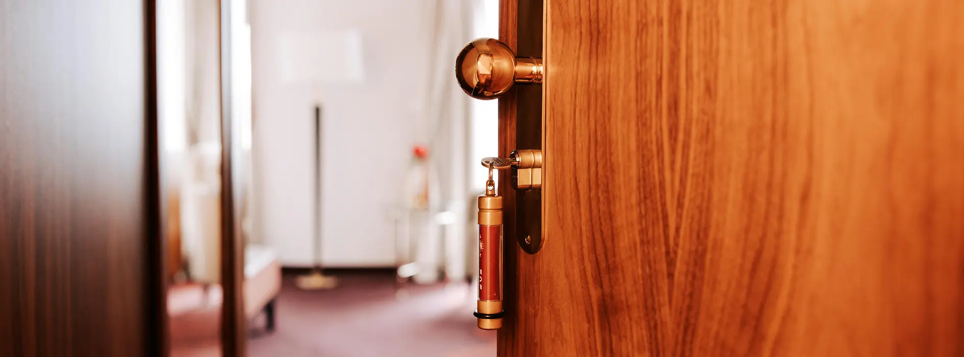 A half-open wooden door leading to a guest room at Hotel Stefanie. The key is in the lock.