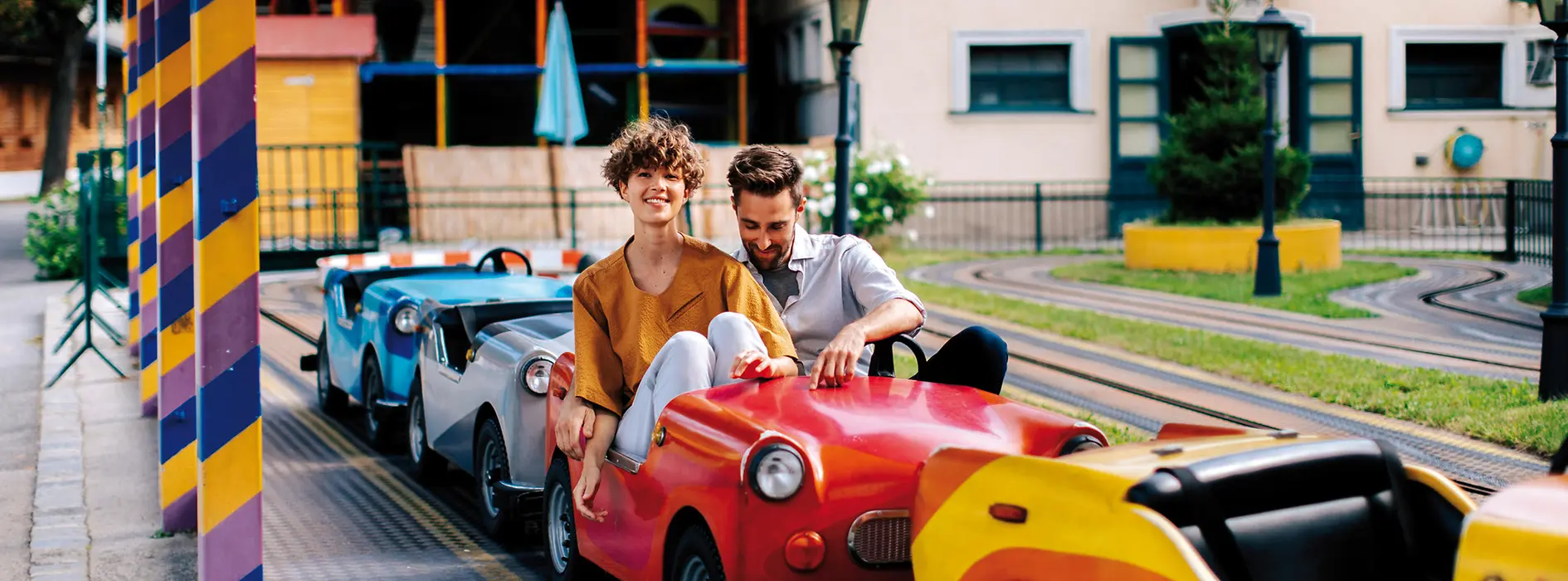 Monza children’s car ride at the Prater. A man and a woman are sitting in a red children’s car.