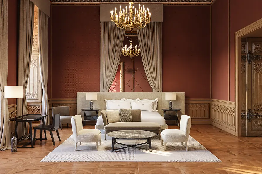Spacious suite with red walls, parquet flooring, a chandelier, a large bed, and a seating area in a historic room.