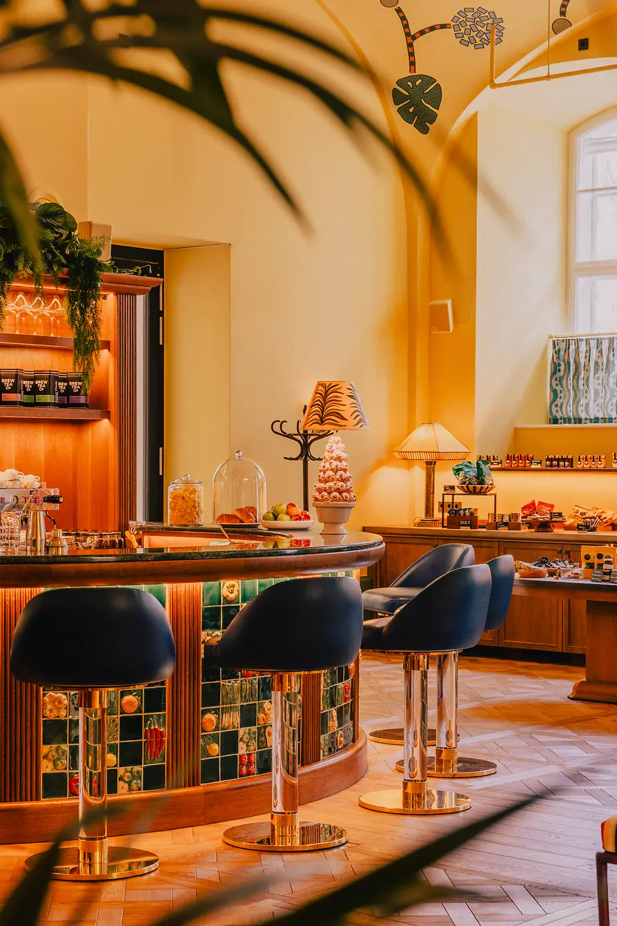 Curved bar with glossy stools, decorative tiles, warm lighting, and product shelves in the background.