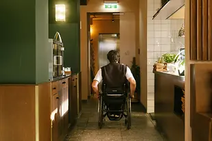 A man using a wheelchair is moving through the interior of magdas Lokal towards an elevator. The image shows accessible wayfinding inside the venue.