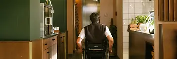 A man using a wheelchair is moving through the interior of magdas Lokal towards an elevator. The image shows accessible wayfinding inside the venue.
