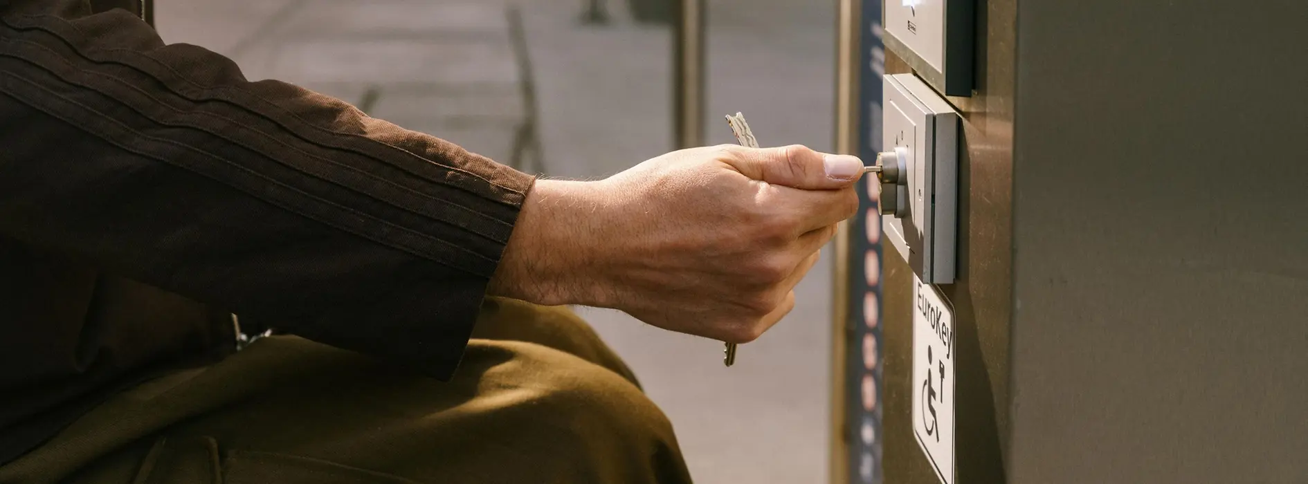 A person using a wheelchair uses a Eurokey at the elevator to MQ Libelle in the public area of the MuseumsQuartier. The image shows accessible access via a Eurokey system.