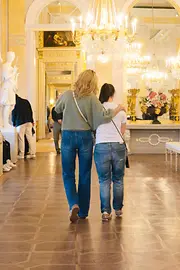Zwei Personen gehen gemeinsam durch einen großzügigen Ausstellungsraum der Albertina. Das Bild zeigt barrierefreie Wegeführung und Orientierung im Museum.