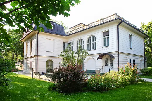 Klimt Villa surrounded by an extensive garden with flowerbeds and trees.