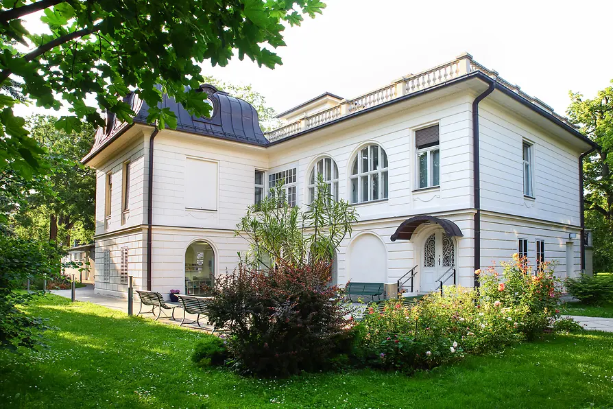 Klimt Villa surrounded by an extensive garden with flowerbeds and trees.