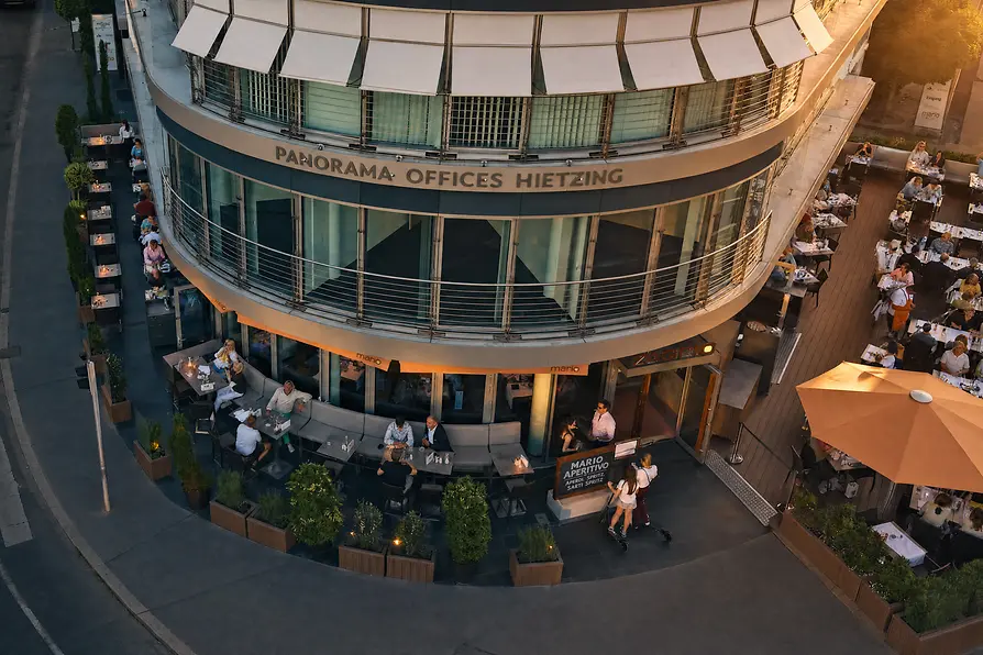 Aerial view of Mario restaurant with spacious terraces and numerous guests at sunset.