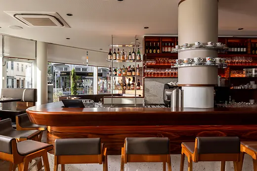 Interior of the Mario bar with wooden counter, coffee machine, spirits and glasses.