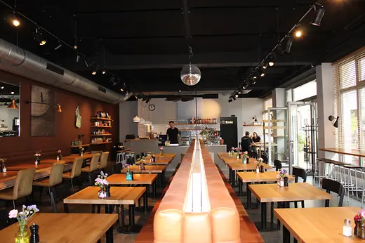 Interior of Waldemar restaurant with wooden tables, leather benches, a bar and a disco ball.