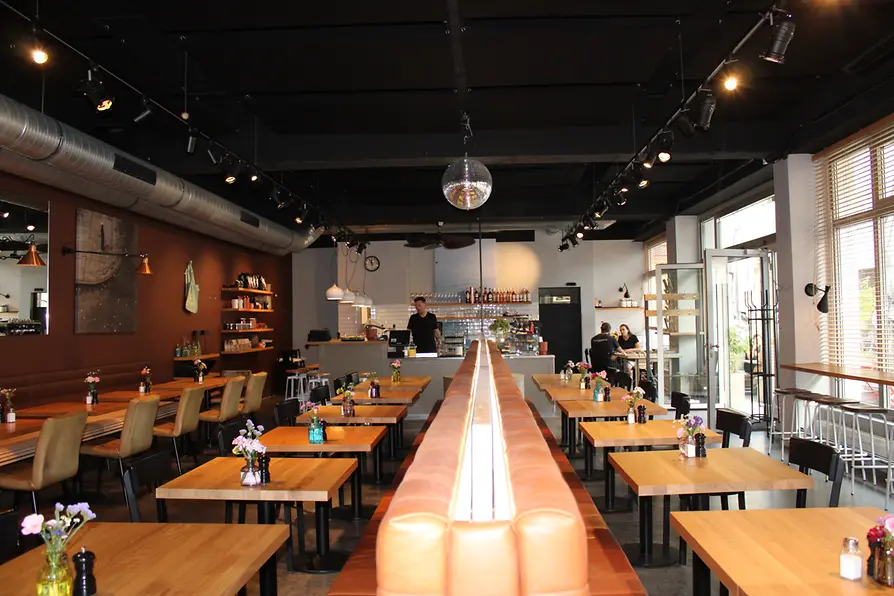 Interior of Waldemar restaurant with wooden tables, leather benches, a bar and a disco ball.