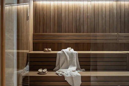Wooden sauna at Almanac Palais Vienna with benches, towels and a sauna bucket.