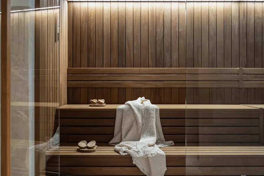 Wooden sauna at Almanac Palais Vienna with benches, towels and a sauna bucket.