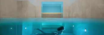 Indoor pool at Almanac Palais Vienna with a swimmer.