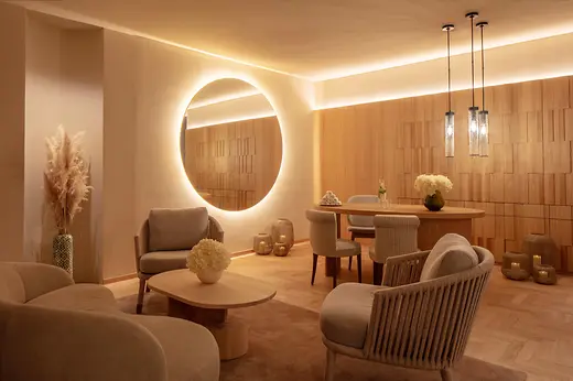 Spa reception at Anantara Palais Hansen Vienna with a round illuminated mirror, wood panelling and seating area.