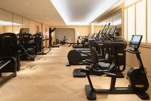 Fitness room at Mandarin Oriental, Vienna with exercise equipment and wooden flooring.