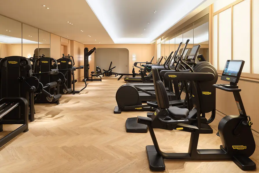 Fitness room at Mandarin Oriental, Vienna with exercise equipment and wooden flooring.