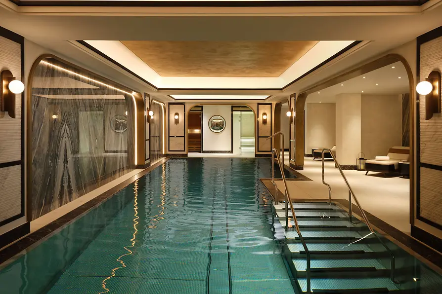 Indoor pool at Mandarin Oriental, Vienna with marble details, loungers and warm lighting.