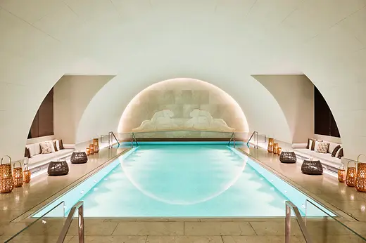Pool area in the Arany Spa at Park Hyatt Vienna with an illuminated indoor pool, benches and decorative lanterns.