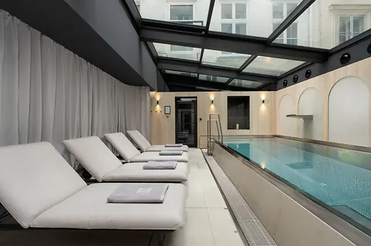 Spa area at The Amauris with loungers and an indoor pool beneath a glass roof.