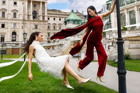 Kampagnenbild „Wanderful Vienna 2026“: Zwei Frauen in Kleidern schweben im Burggarten