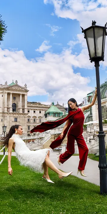 Kampagnenbild „Wanderful Vienna 2026“: Zwei Frauen in Kleidern schweben im Burggarten