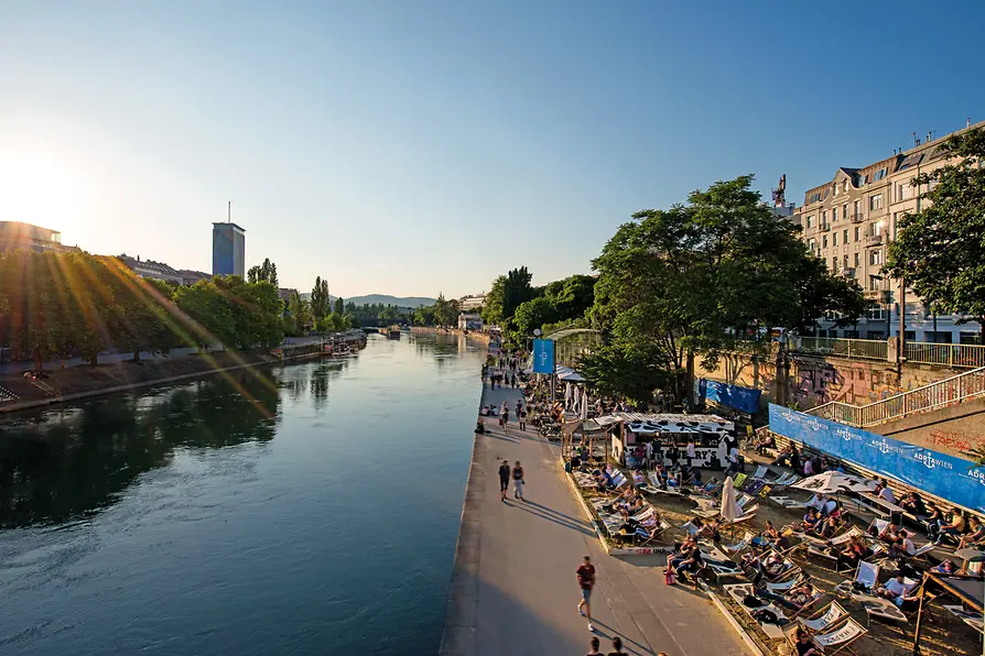 People lying in the sun on loungers by the Danube Canal