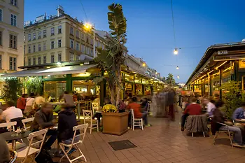 Bustling scene in the pubs and cafes at Naschmarkt, exterior shot with people 