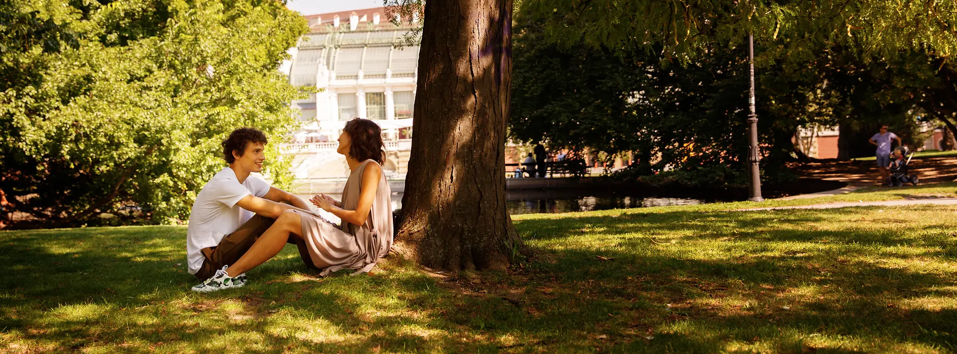 Paar sitzt im Wiener Burggarten unter Bäumen