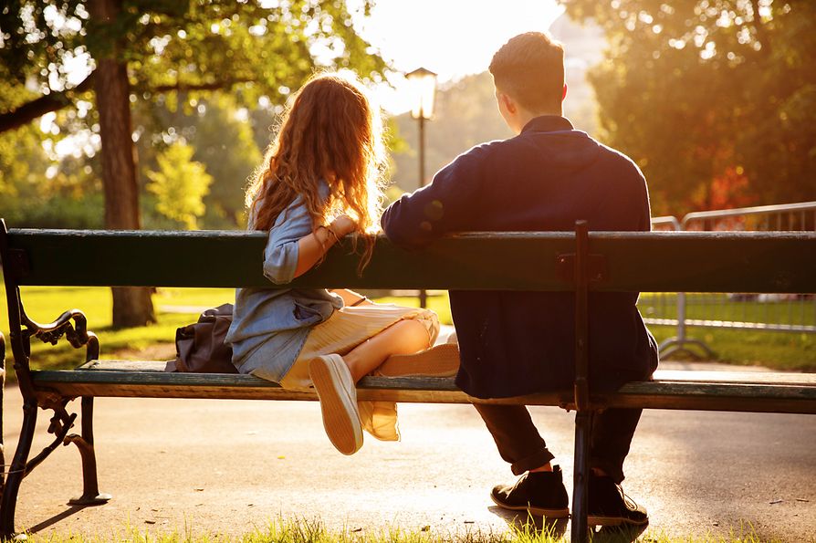 Jugendliches Paar sitzt auf einer Parkbank im Burggarten