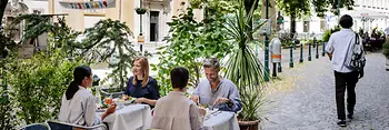 Menschen sitzen in einem Gastgarten